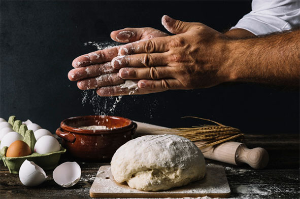 Foto de uma mão preparando uma massa de pão